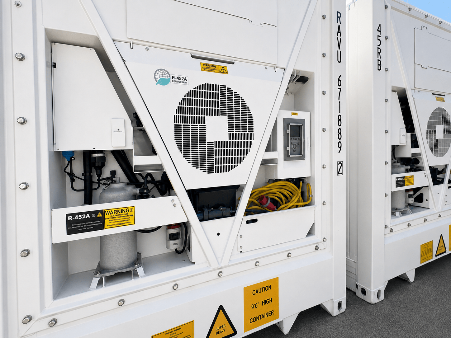 White industrial equipment featuring a large fan, yellow cables, and warning labels on a grey surface.