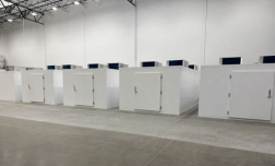 Five large, white walk-in cold rooms with blue tops, set against a plain white wall.